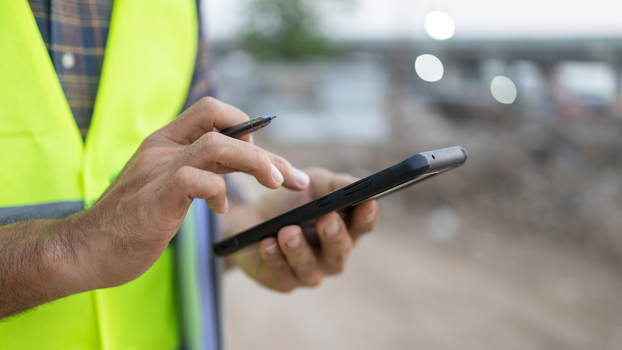 Mann auf der Baustelle füll eine Checkliste auf dem Smartphone aus